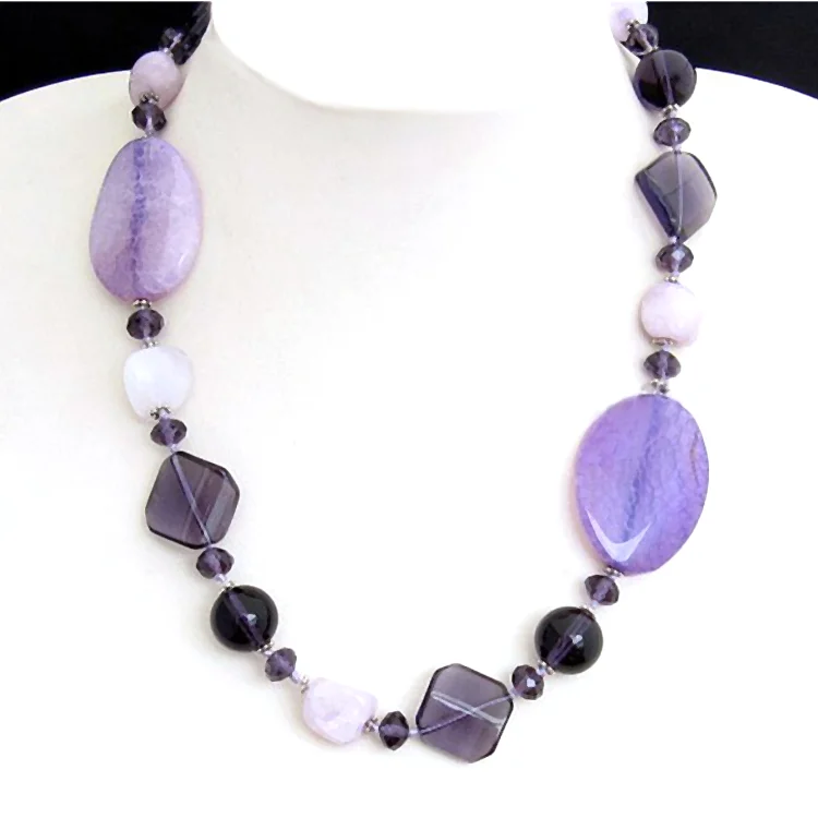 Halsband av agat-ädelsten, rondeller och slipade kristaller. 50cm långt designsmycke i ljusviolett till violett. Utsökt kvalitet.